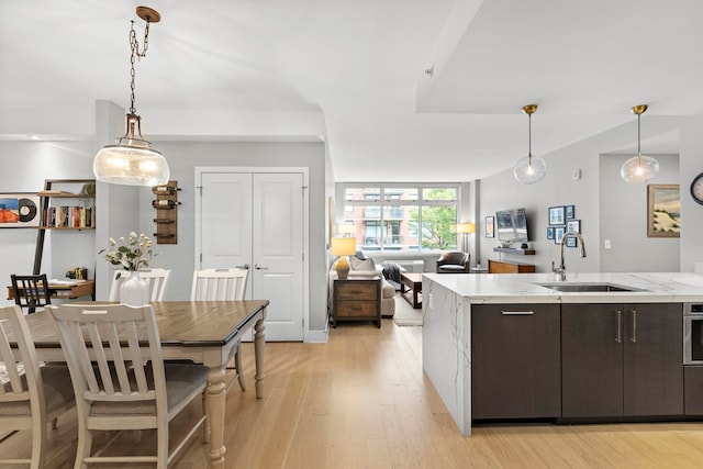 1400 Hudson St Unit 511, Hoboken, NJ 07030 - kitchen featuring dark brown cabinetry, light wood-style floors, open floor plan, and pendant lighting