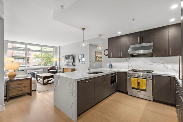 1400 Hudson St Unit 511, Hoboken, NJ 07030 - kitchen with stainless steel stove, under cabinet range hood, a peninsula, light wood finished floors, and recessed lighting