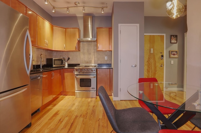 1034 Clinton St Unit 208, Hoboken, NJ 07030 - kitchen featuring stainless steel appliances, wall chimney exhaust hood, light wood-style floors, decorative backsplash, and dark countertops