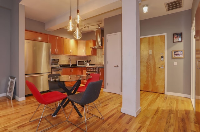 1034 Clinton St Unit 208, Hoboken, NJ 07030 - kitchen with stainless steel appliances, wall chimney exhaust hood, decorative backsplash, dark countertops, and light wood-style flooring