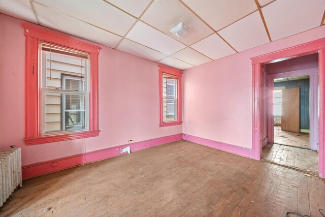 152 Bidwell Ave, Jersey City, NJ 07305 - empty room featuring radiator heating unit, hardwood / wood-style floors, a drop ceiling, and healthy amount of natural light