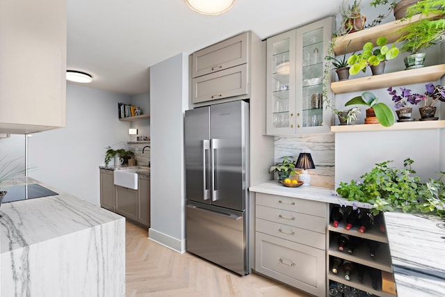 kitchen with high end fridge, open shelves, gray cabinets, a sink, and black electric stovetop