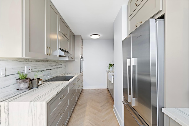 kitchen with stainless steel appliances, gray cabinetry, backsplash, under cabinet range hood, and light stone counters