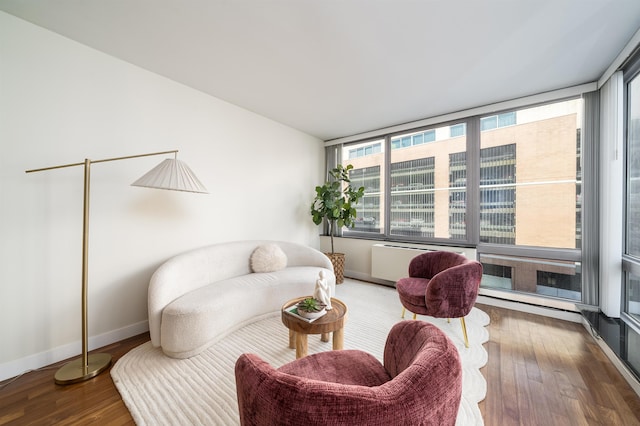 living area with hardwood / wood-style flooring and radiator heating unit