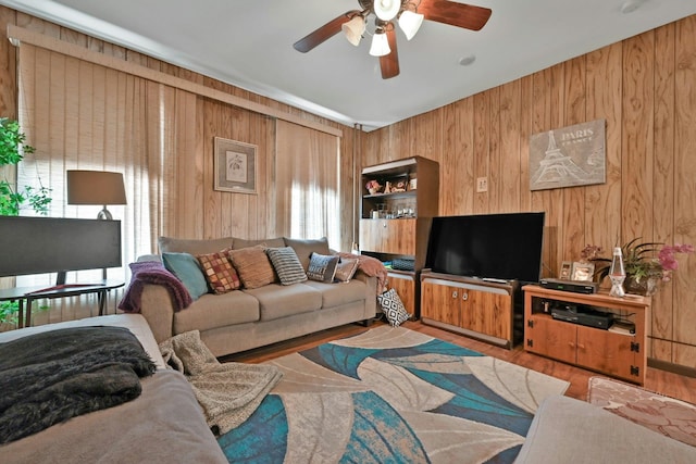 living room with light hardwood / wood-style floors, ceiling fan, and wood walls