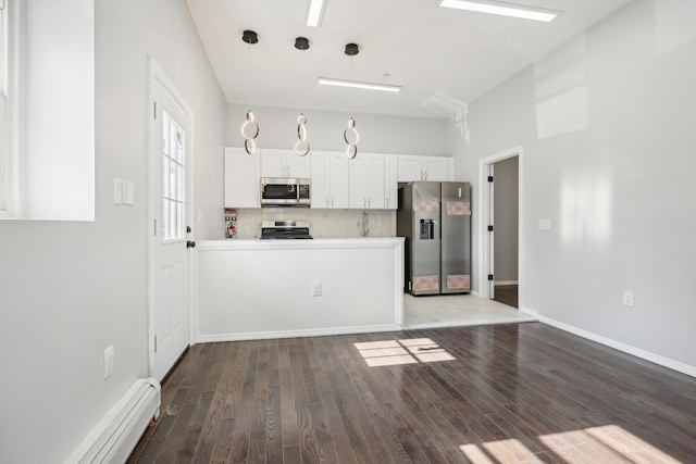 kitchen with dark wood-style floors, a baseboard radiator, stainless steel appliances, white cabinetry, and backsplash