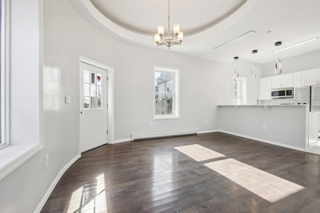 unfurnished dining area with dark wood-style floors, a tray ceiling, baseboards, and baseboard heating