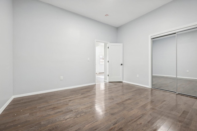 unfurnished bedroom with a closet, wood finished floors, and baseboards