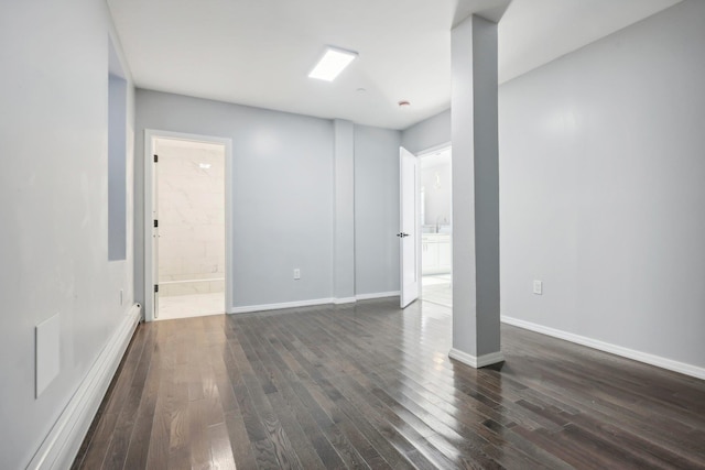 below grade area with a baseboard radiator, baseboards, and dark wood-style flooring