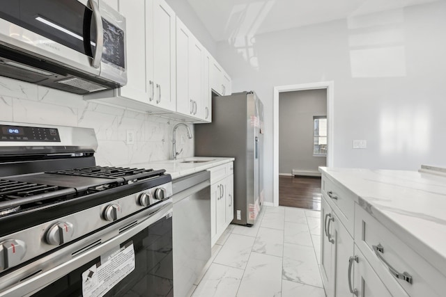 kitchen with light stone counters, a sink, marble finish floor, appliances with stainless steel finishes, and backsplash