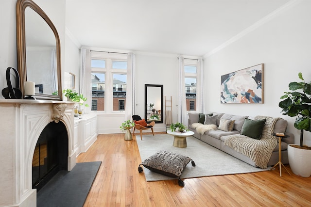 living area featuring ornamental molding, light wood-style floors, and a fireplace with flush hearth