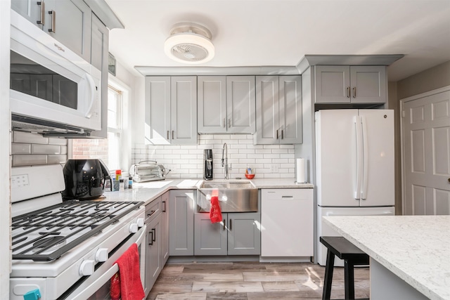 104 W 52nd St, Bayonne, NJ 07002 - kitchen with backsplash, gray cabinets, a sink, and white appliances