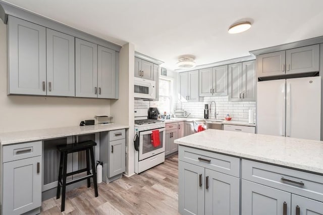 104 W 52nd St, Bayonne, NJ 07002 - kitchen featuring a sink, light wood-style floors, decorative backsplash, white appliances, and gray cabinets