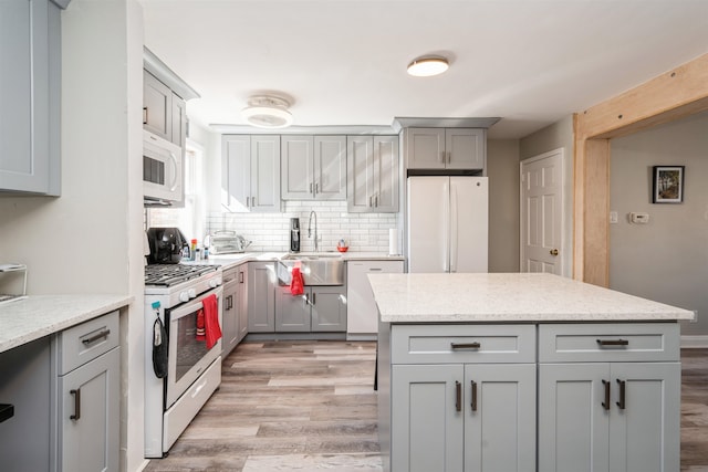 104 W 52nd St, Bayonne, NJ 07002 - kitchen with a sink, decorative backsplash, white appliances, light wood finished floors, and gray cabinetry