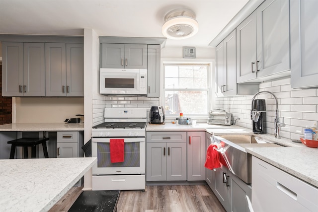 104 W 52nd St, Bayonne, NJ 07002 - kitchen featuring gray cabinets, backsplash, and white appliances