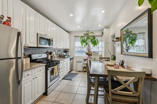 6607 Kennedy Blvd, North Bergen, NJ 07047 - kitchen with appliances with stainless steel finishes, white cabinetry, recessed lighting, light tile patterned flooring, and tasteful backsplash