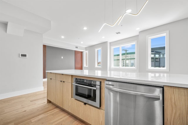 kitchen with stainless steel appliances, light hardwood / wood-style flooring, and light brown cabinets