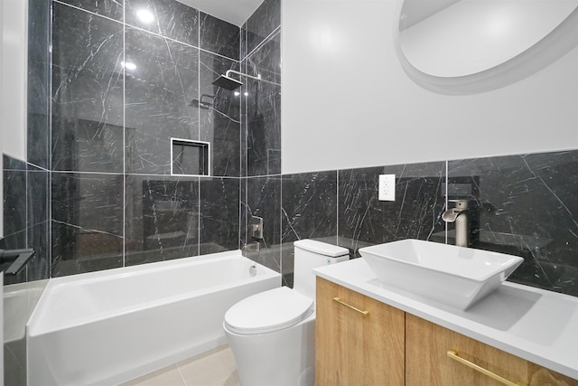 full bathroom featuring tiled shower / bath, vanity, toilet, and tile walls