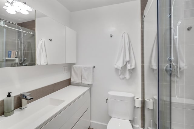 bathroom with a shower with door, vanity, and toilet