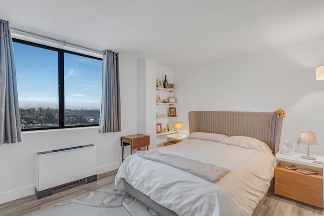 bedroom with radiator and light wood-type flooring