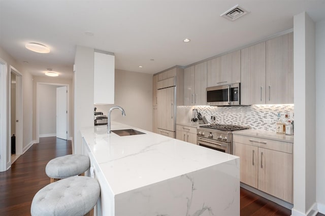 kitchen with sink, light stone countertops, a kitchen bar, dark wood-type flooring, and high quality appliances