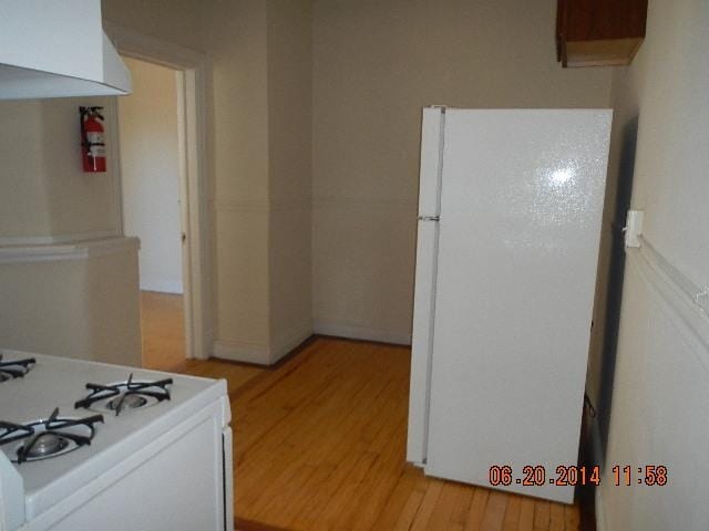 kitchen featuring white cabinets, white appliances, and light wood-type flooring