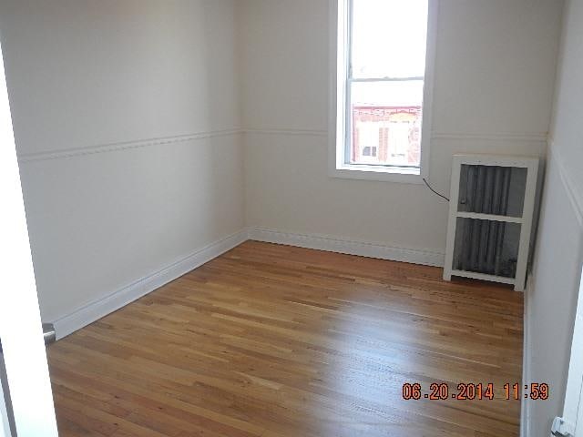 unfurnished room with hardwood / wood-style floors and radiator