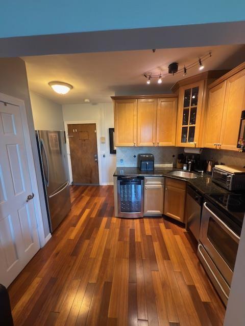 108 Waldo Ave Unit 4A, Jersey City, NJ 07306 - kitchen featuring appliances with stainless steel finishes, glass insert cabinets, dark countertops, dark wood-type flooring, and tasteful backsplash