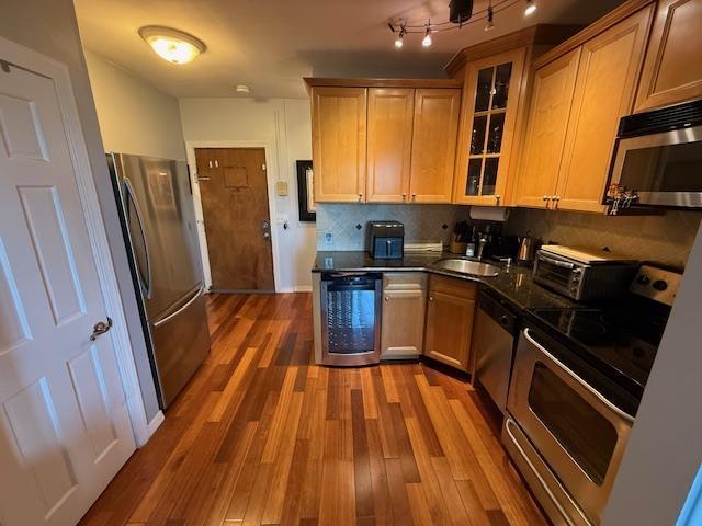 108 Waldo Ave Unit 4A, Jersey City, NJ 07306 - kitchen with appliances with stainless steel finishes, dark countertops, wood finished floors, glass insert cabinets, and decorative backsplash