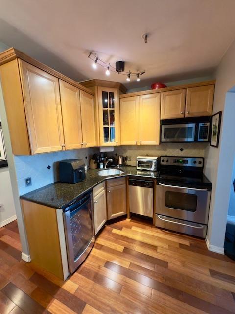 108 Waldo Ave Unit 4A, Jersey City, NJ 07306 - kitchen featuring appliances with stainless steel finishes, light wood-style flooring, glass insert cabinets, and dark stone countertops