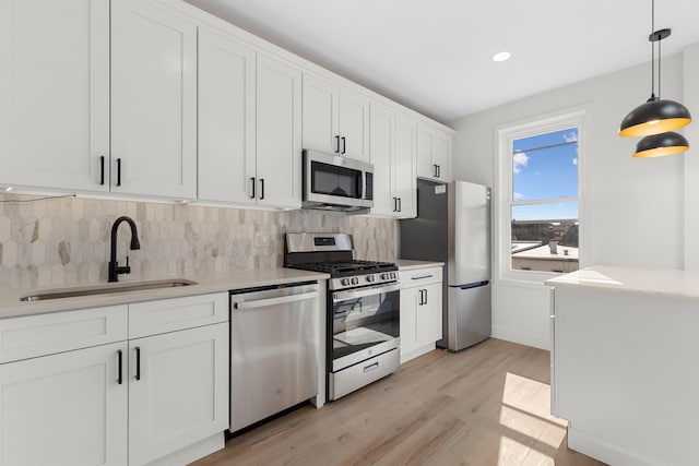 kitchen with a sink, white cabinets, light countertops, appliances with stainless steel finishes, and backsplash