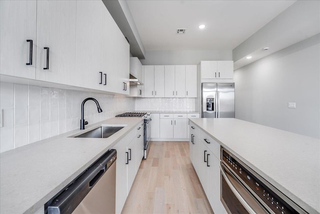 810 6th St, Union City, NJ 07087 - kitchen with appliances with stainless steel finishes, a sink, light wood-type flooring, light countertops, and backsplash