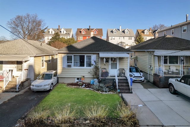 view of front of house with driveway, a shingled roof, a front yard, and a residential view