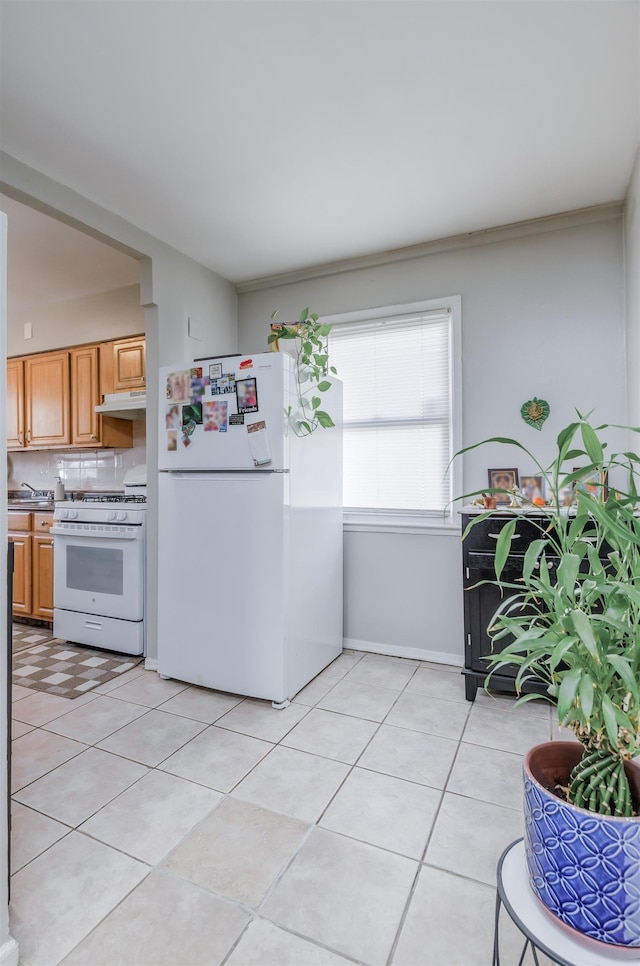 kitchen with tasteful backsplash, light tile patterned floors, and white appliances