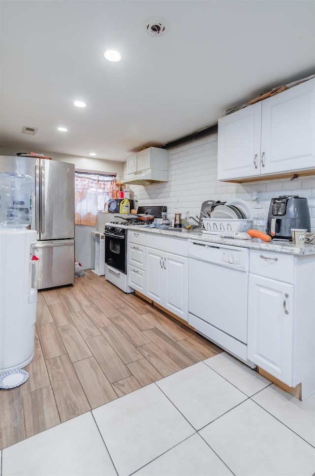 kitchen with dishwasher, gas range oven, stainless steel fridge, light hardwood / wood-style floors, and white cabinets