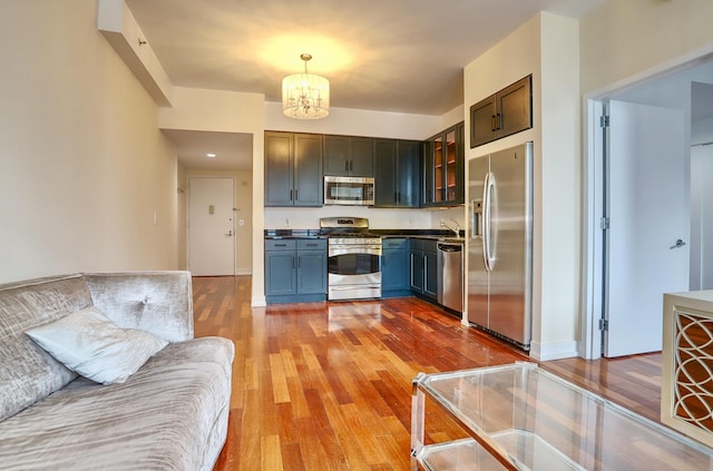 389 Washington St Unit 30C, Jersey City, NJ 07302 - kitchen featuring stainless steel appliances, a chandelier, wood finished floors, glass insert cabinets, and open floor plan