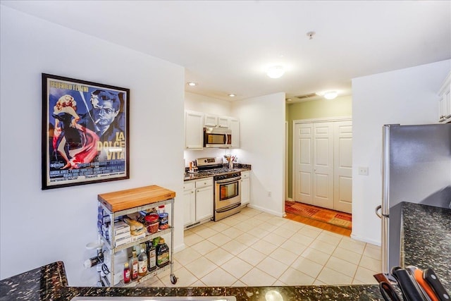 252 The Promenade Unit 252, Edgewater, NJ 07020 - kitchen featuring stainless steel appliances, light tile patterned floors, white cabinetry, and dark stone counters