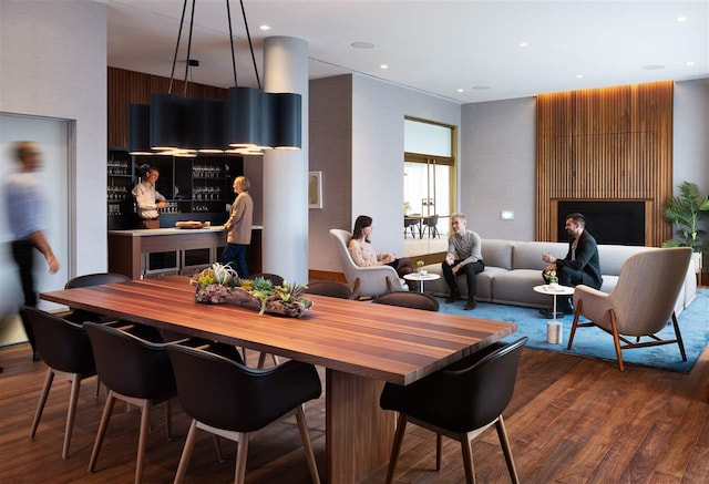 dining room with dark wood-style flooring, a fireplace, and recessed lighting