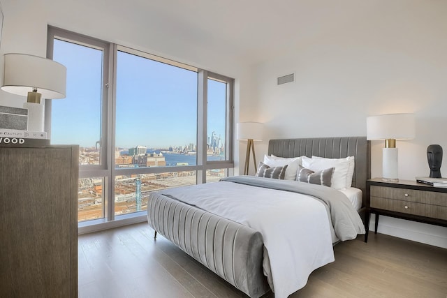 bedroom with a view of city, visible vents, and wood finished floors