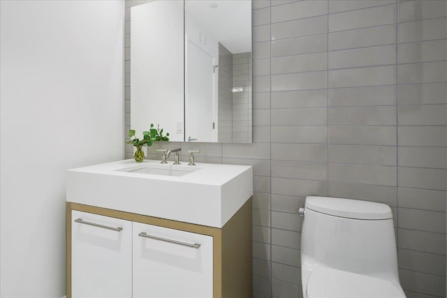 bathroom with toilet, tile walls, and vanity