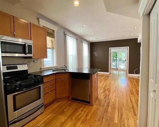 152 Highland Ave Unit 2B, Jersey City, NJ 07306 - kitchen featuring appliances with stainless steel finishes, a peninsula, brown cabinetry, light wood-style floors, and dark countertops