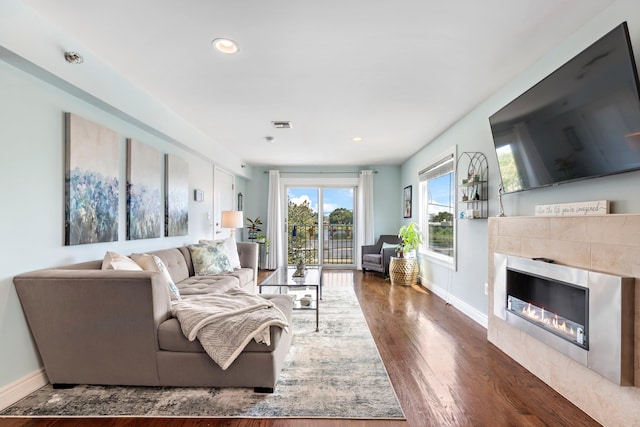 living area with visible vents, baseboards, wood finished floors, and a tile fireplace