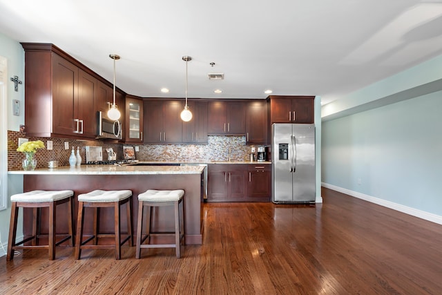 kitchen featuring stainless steel appliances, a peninsula, dark brown cabinets, decorative backsplash, and glass insert cabinets