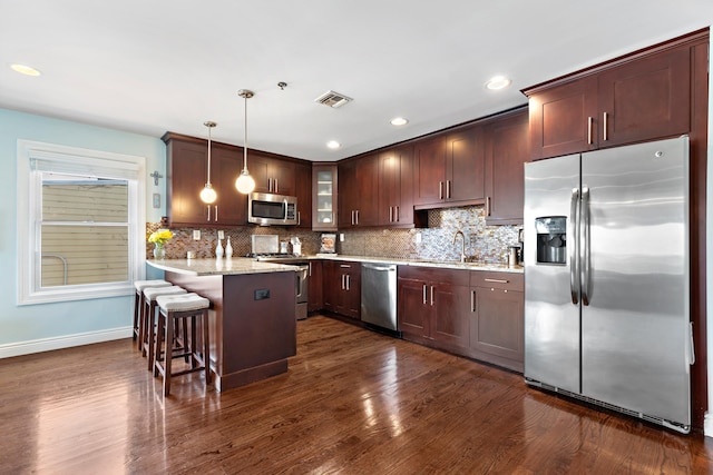 kitchen with stainless steel appliances, dark wood-type flooring, a peninsula, visible vents, and backsplash