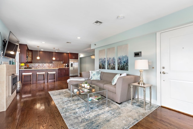 living room featuring dark wood-type flooring, recessed lighting, and visible vents