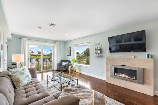 living room with a tile fireplace, recessed lighting, visible vents, baseboards, and dark wood-style floors