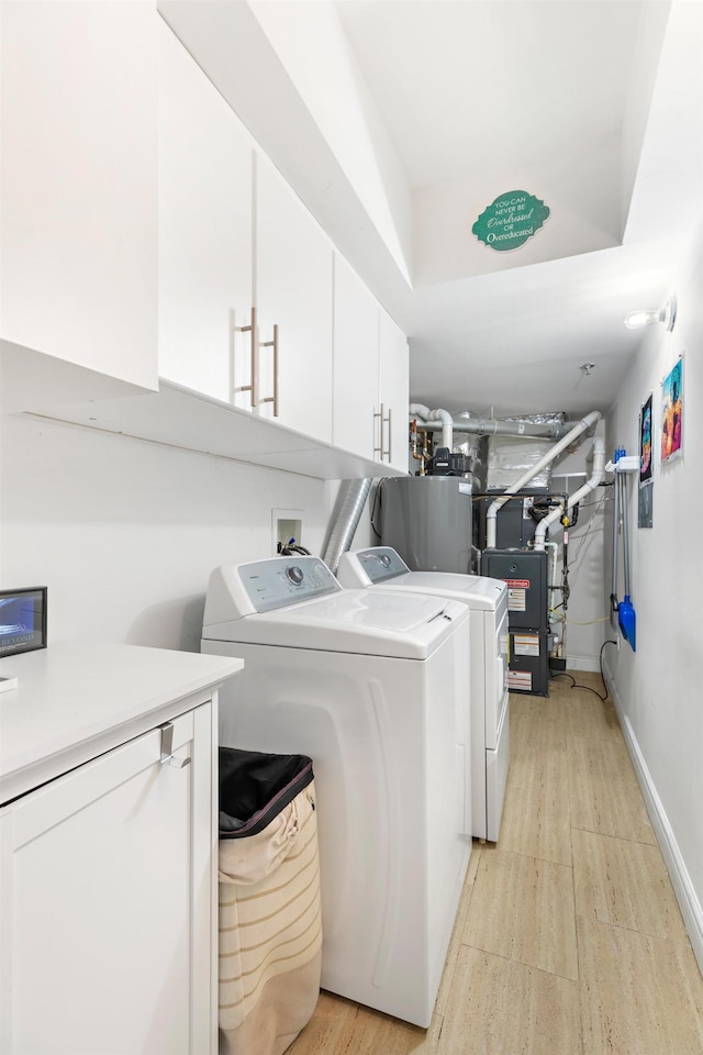 laundry area with cabinet space, washing machine and dryer, water heater, and baseboards