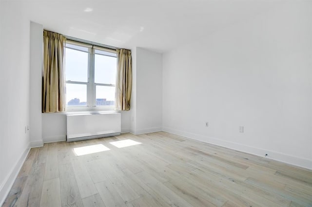 unfurnished room with light wood-style flooring and baseboards