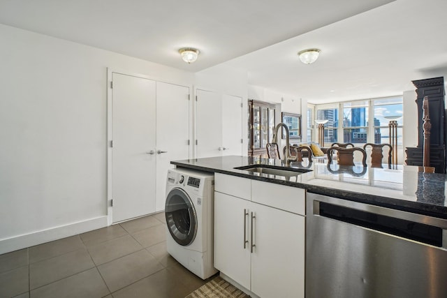 washroom featuring baseboards, laundry area, washer / clothes dryer, a sink, and dark tile patterned floors