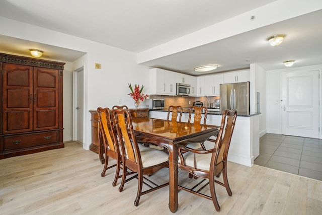 dining space featuring light wood-type flooring and baseboards